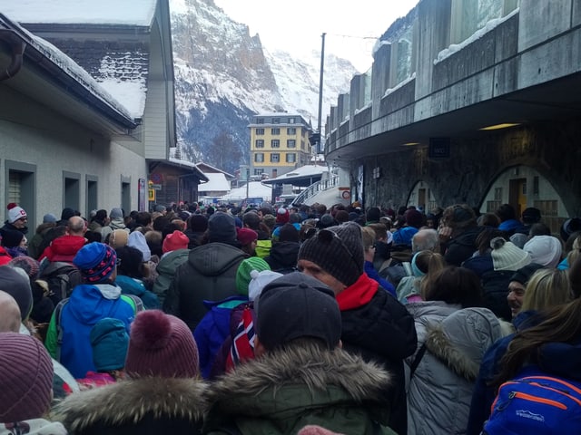 Viele Menschen in einer Strasse, im Hintergrund Blick auf Berge
