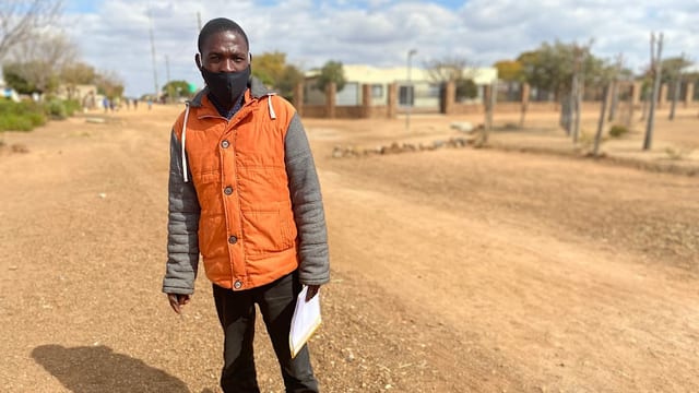 Sozialarbeiter Frans Magwele zu Fuss unterwegs auf einer Landstrasse Sozialarbeiter Frans Magwele zu Fuss unterwegs auf einer Landstrasse