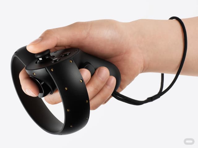 Eine Hand hält eine Oculus Touch, eine Art Pistole mit mondförmigen Kreis um den Lauf.