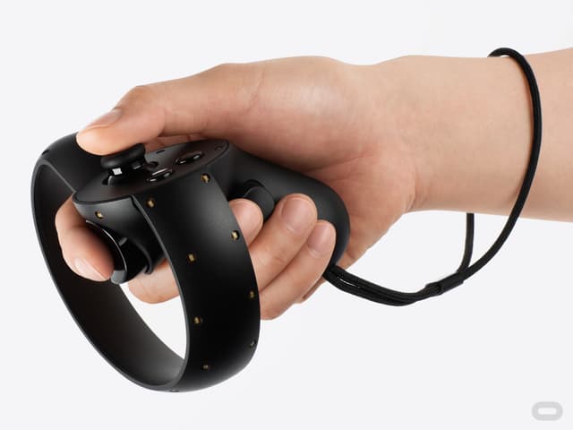 Eine Hand hält eine Oculus Touch, eine Art Pistole mit mondförmigen Kreis um den Lauf. Eine Hand hält eine Oculus Touch, eine Art Pistole mit mondförmigen Kreis um den Lauf.