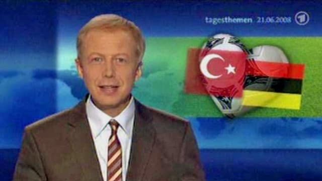Ein Moderator preist ein Fussballspiel an – im Hintergrund ist die falsche Deutschlandflagge eingeblendet. 