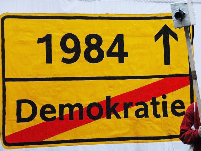 Verkehrsschild mit «1984» und dem Wort Demokratie durchgestrichen als Ortsausfahrt. Verkehrsschild mit «1984» und dem Wort Demokratie durchgestrichen als Ortsausfahrt.