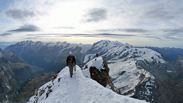 Ein Bergsteiger auf einem verschneiten Grat. Ein Bergsteiger auf einem verschneiten Grat.