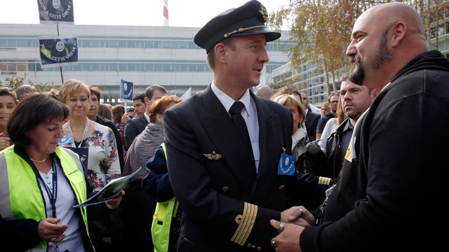 Streikender Air-France-Pilot spricht an einer Kundgebung mit einem Passanten Streikender Air-France-Pilot spricht an einer Kundgebung mit einem Passanten