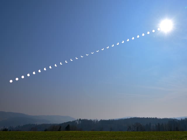 Blauer Himmel mit Sonne rechts oben. Viele kleine Momentaufnahmen der Sonnenfinsternis mit verschiedenen Stadien.