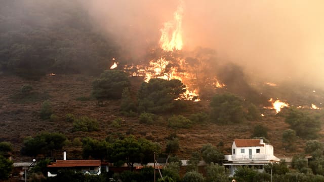 Athener Stadtteils Kareas. Mächtige Flammen stechen aus einem Waldstück in der Nähe von Wohnhäusern im Athener Stadtteil Kareas. Athener Stadtteils Kareas. Mächtige Flammen stechen aus einem Waldstück in der Nähe von Wohnhäusern im Athener Stadtteil Kareas.