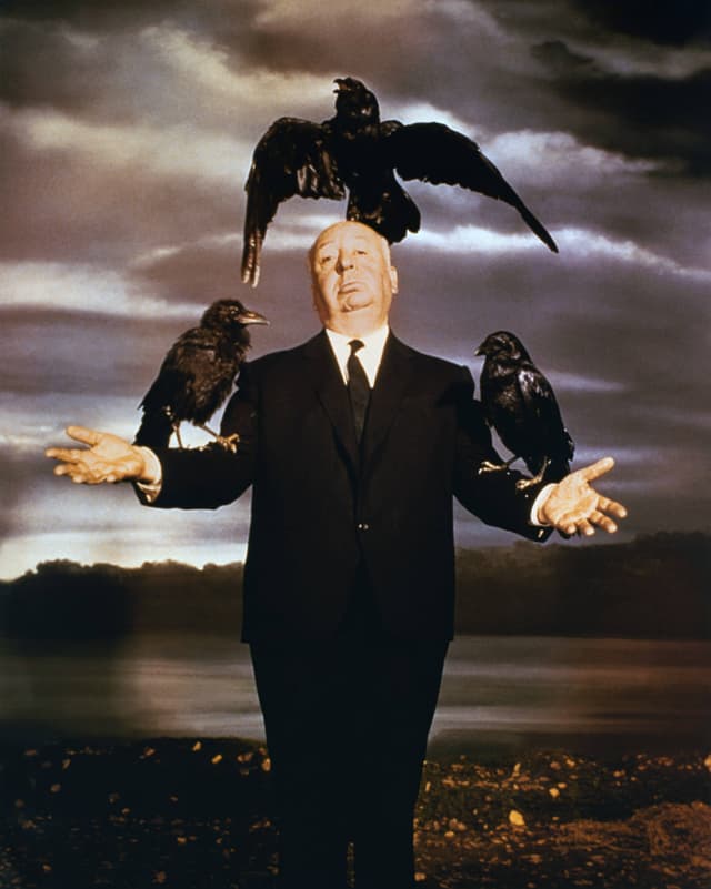 Promo-Foto des Films «Die Vögel»: Regisseur Alfred Hitchcock posiert als Vogelscheuche mit drei Krähen auf Kopf und Armen. Promo-Foto des Films «Die Vögel»: Regisseur Alfred Hitchcock posiert als Vogelscheuche mit drei Krähen auf Kopf und Armen.