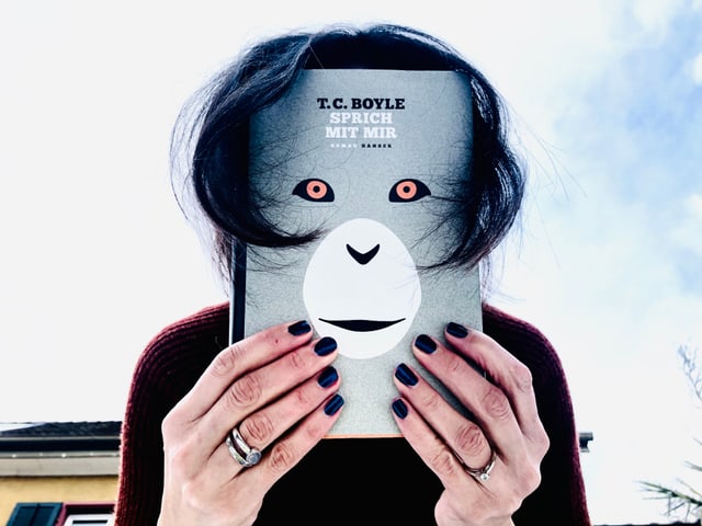 Annette König hält sich den Roman «Sprich mit mir» von T.C. Boyle vor das Gesicht