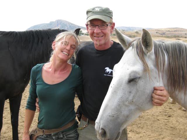 Eine Frau und ein Mann posieren für das Foto. Neben ihn stehen zwei Pferde. Eine Frau und ein Mann posieren für das Foto. Neben ihn stehen zwei Pferde.