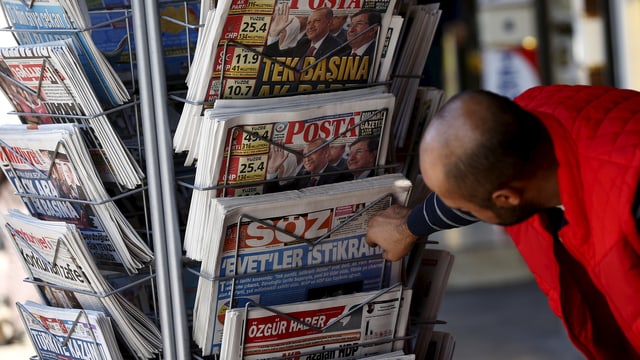 Zeitungen an einem Kisok in der Türkei, ein Mann beugt sich zu einem Exemplar hinunter. Zeitungen an einem Kisok in der Türkei, ein Mann beugt sich zu einem Exemplar hinunter.