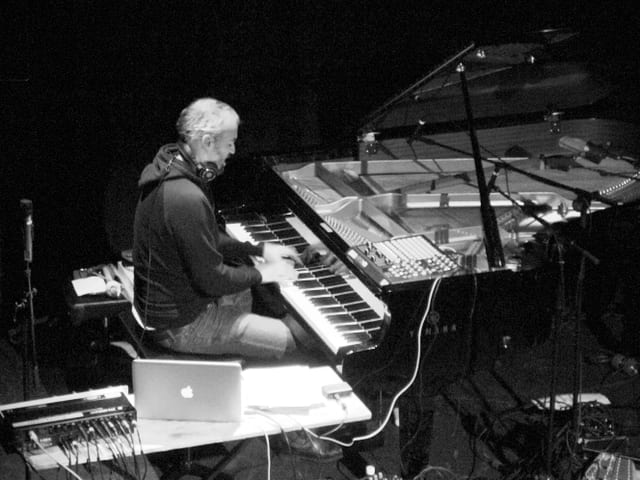 Ein Musiker an einem Flügel, daneben ein Computer und Synthesizer. Ein Musiker an einem Flügel, daneben ein Computer und Synthesizer.