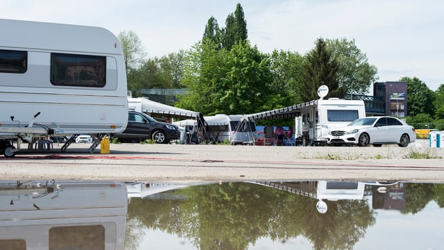 Vorne eine Pfütze, links ein Wohnwagen, weiter hinten ein Wohnmobil und ein Personenwagen. Vorne eine Pfütze, links ein Wohnwagen, weiter hinten ein Wohnmobil und ein Personenwagen.