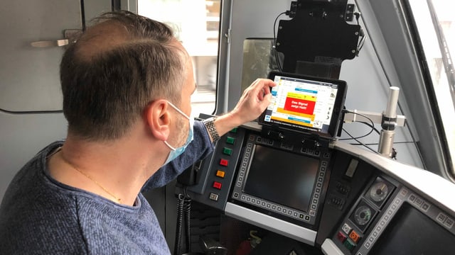 Ein Lokomitivführer bedient einen Touchscreen im Führerstand.