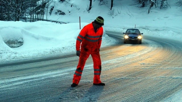 Mann in oranger Kleidung auf vereister Strasse. Mann in oranger Kleidung auf vereister Strasse.