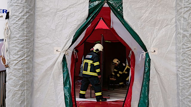 Weisses Zelt ist einen Spalt geöffnet, darin Männer in Anzügen. Weisses Zelt ist einen Spalt geöffnet, darin Männer in Anzügen.