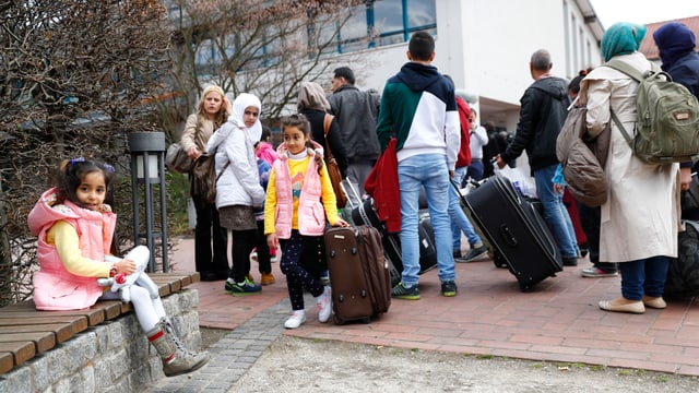 Migranten mit Koffern vor einem grossen Gebäude in Deutschland. Migranten mit Koffern vor einem grossen Gebäude in Deutschland.