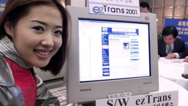 Eine Asiatin lächelt neben einem Bildschirm mit Übersetzungs-Software. Eine Asiatin lächelt neben einem Bildschirm mit Übersetzungs-Software.