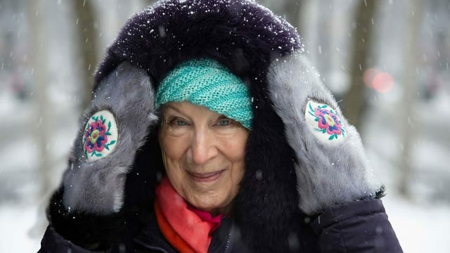 Alte Frau im Winter mit Handschuhen und Kaputze