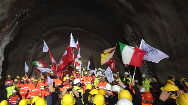Bauarbeiter in einem Tunnel: Sie schwenken verschiedene Flaggen. Bauarbeiter in einem Tunnel: Sie schwenken verschiedene Flaggen.