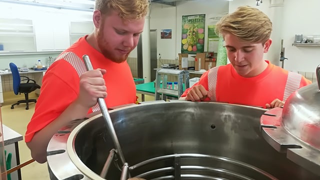 Zwei junge Männer stehen um ein Metallbehälter Zwei junge Männer stehen um ein Metallbehälter