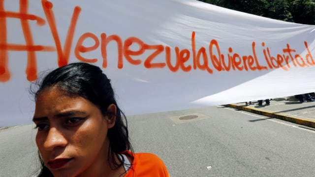 Venezolanische Demonstrantin vor einem Banner Venezolanische Demonstrantin vor einem Banner