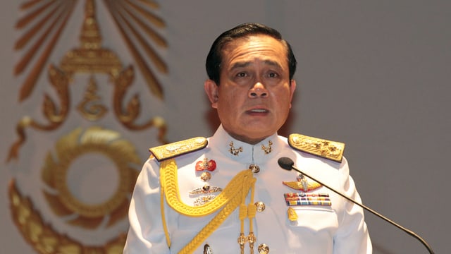 Ein Mann in einer weissen Militäruniform steht an einem Mikrofon. Ein Mann in einer weissen Militäruniform steht an einem Mikrofon.