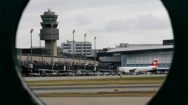 Durch ein rundes Loch blickt man auf den Kontrollturm aus Beton am Flughafen Zürich. Durch ein rundes Loch blickt man auf den Kontrollturm aus Beton am Flughafen Zürich.