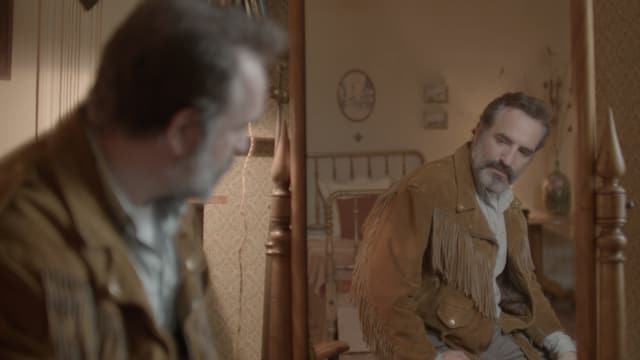 Ein Mann, der eine Lederjacke trägt, blickt sich im Spiegel an. Ein Mann, der eine Lederjacke trägt, blickt sich im Spiegel an.