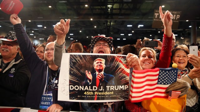 Jubelnde Menschen mit Amerkia-Flagge und Poster von Donald Trump. Jubelnde Menschen mit Amerkia-Flagge und Poster von Donald Trump.