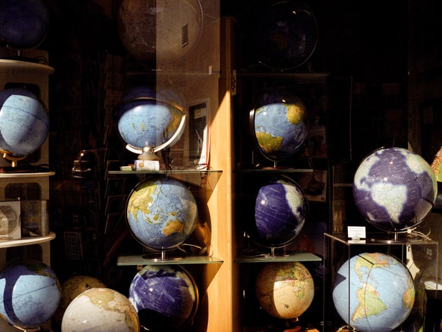 Ein Schaufenster mit einem Regal, in dem alte Weltkugeln stehen. Ein Schaufenster mit einem Regal, in dem alte Weltkugeln stehen.