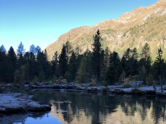 Der Lagh da Saoseo liegt im Schatten der Gegenhang im strahlenden Sonnenschein.
