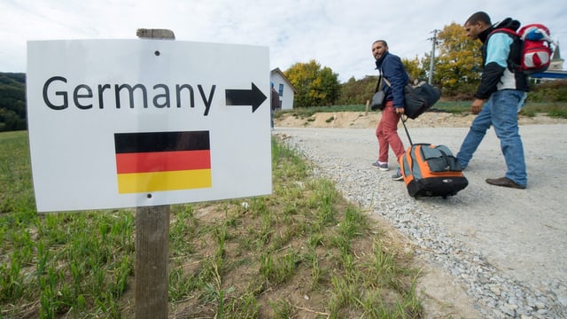 Zwei Flüchtlinge passieren ien Schild mit der Aufschrift «Germany». Zwei Flüchtlinge passieren ien Schild mit der Aufschrift «Germany».