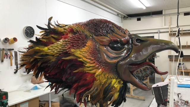 Eine fertige Vogelmaske mit rot-gelben Federn. Eine fertige Vogelmaske mit rot-gelben Federn.
