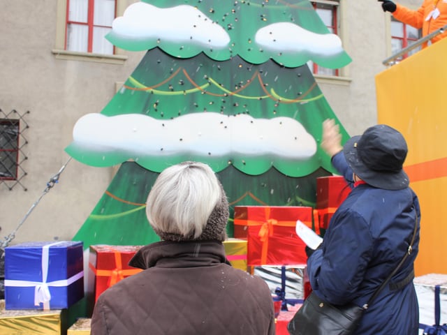 Zwei Frauen werfen ein Licht an den SRF 1-Tannenbaum.
