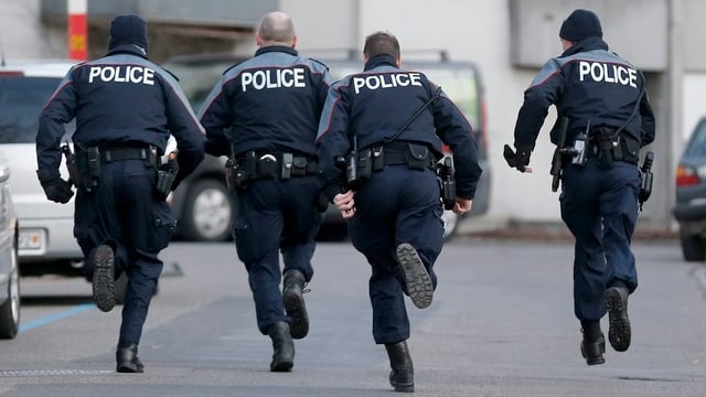 Berner Polizisten rennen durch eine Strasse. Berner Polizisten rennen durch eine Strasse.