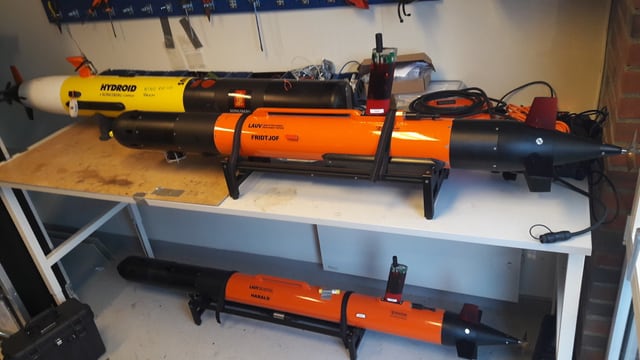 Drei torpedoförmige Roboter liegen auf einem Tisch. Drei torpedoförmige Roboter liegen auf einem Tisch.