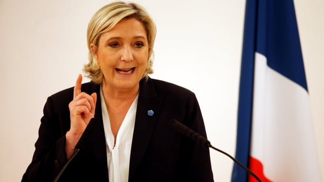 Marine Le Pen mit erhobenem Zeigefinger an einem Rednerpult