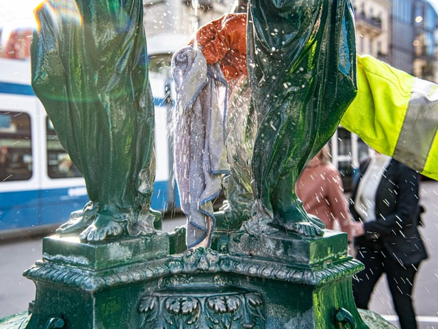 Person reinigt einen kleinen Brunnen Person reinigt einen kleinen Brunnen