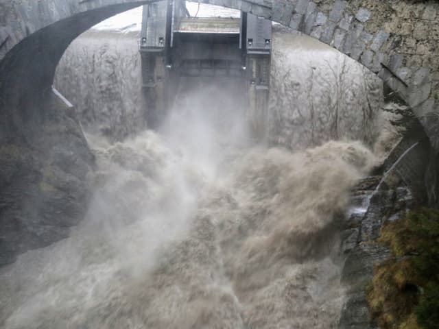 Viel braunes wildes Wasser stürzt über ein Wehr