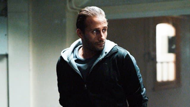 Ein Mann in Lederjacke steht in einem Raum. Ein Mann in Lederjacke steht in einem Raum.
