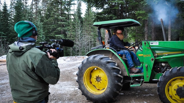 Bärtiger Mann sitzt auf einem grossen Traktor. Bärtiger Mann sitzt auf einem grossen Traktor.