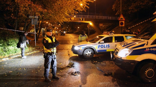 Polizist steht in der Nacht vor mehreren Streifenwagen. Archivbild Polizist steht in der Nacht vor mehreren Streifenwagen. Archivbild