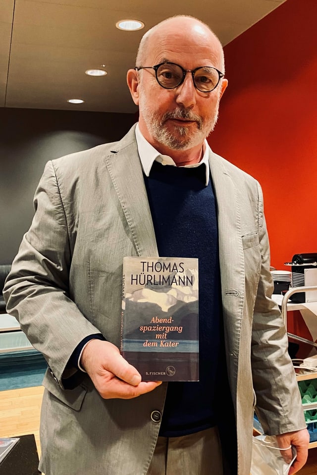 Mann mit Glatze und Brille hält Buch in der Hand Mann mit Glatze und Brille hält Buch in der Hand