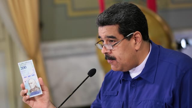 Maduro hält eine Banknote in der Hand Maduro hält eine Banknote in der Hand