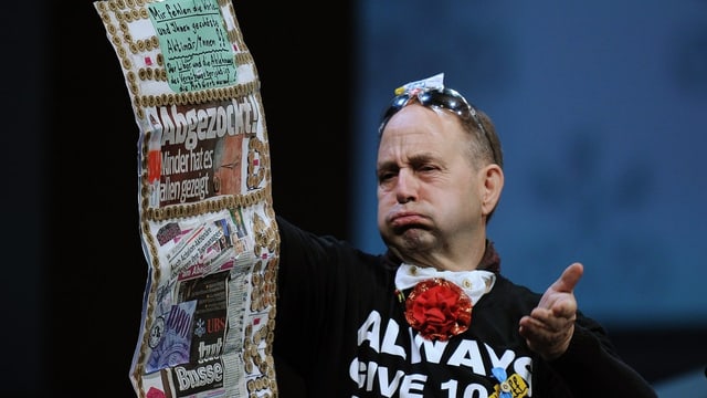Der Aktionär Peter Lampart auf der Bühne an der Generalversammlung der UBS. Er hält Zeitungsausschnitte in der Hand. Der Aktionär Peter Lampart auf der Bühne an der Generalversammlung der UBS. Er hält Zeitungsausschnitte in der Hand.