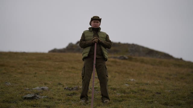 Putin in seinem Urlaub in der sibirischen Taiga auf einer grünen Ebene mit Stock. Putin in seinem Urlaub in der sibirischen Taiga auf einer grünen Ebene mit Stock.