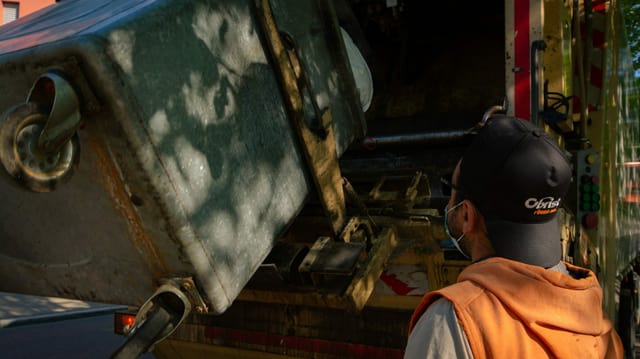Ein Mann schaut wie der Abfall aus dem Container in die Kehrichtabfuhr verladen wird. Ein Mann schaut wie der Abfall aus dem Container in die Kehrichtabfuhr verladen wird.