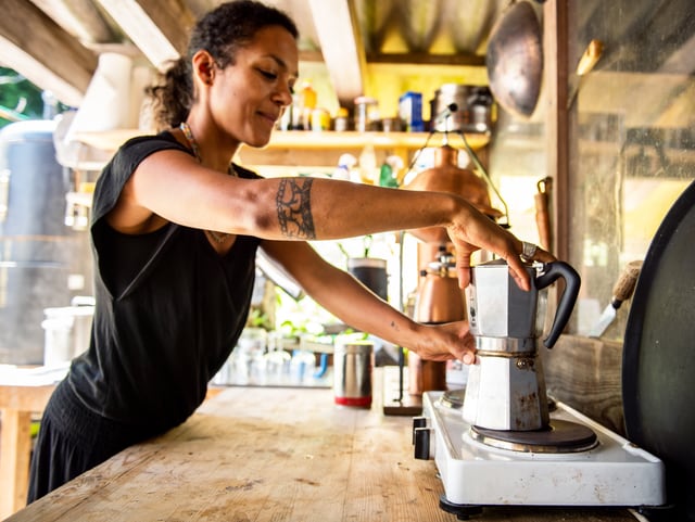 Eine Frau steht vor einer 2er-Herdplatte. Darauf eine Bialetti-Kaffeemaschine. Eine Frau steht vor einer 2er-Herdplatte. Darauf eine Bialetti-Kaffeemaschine.