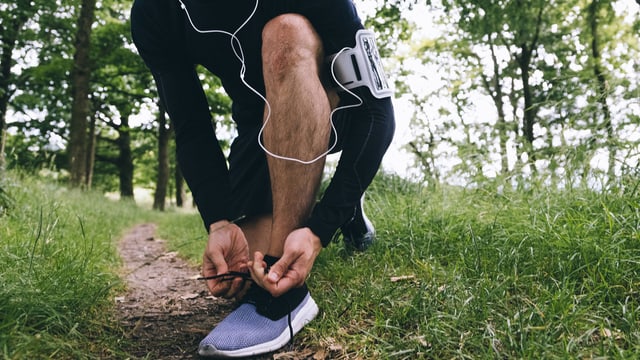 Ein Jogger mit Kopfhörer bindet sich die Schuhe. Ein Jogger mit Kopfhörer bindet sich die Schuhe.