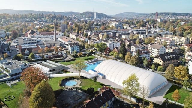 Blick auf eine Anlage mit grünen Wiesen, über einem Schwimmbad ist ein weisses Zelt gespannt. Blick auf eine Anlage mit grünen Wiesen, über einem Schwimmbad ist ein weisses Zelt gespannt.